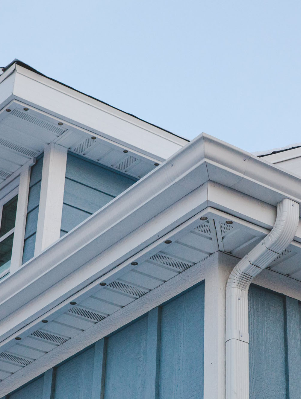 White permanent lighting track blending into a light-colored home soffit and fascia during the day